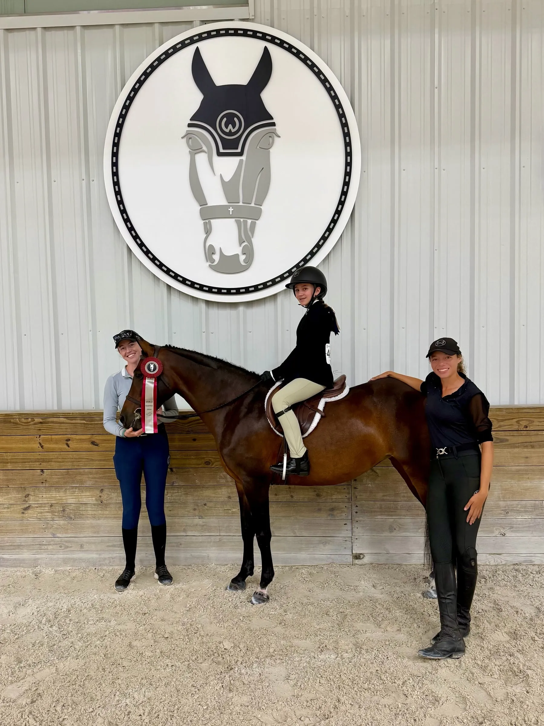 A young rider on a bay pony with her ribbon in the World Equestrian Center arena