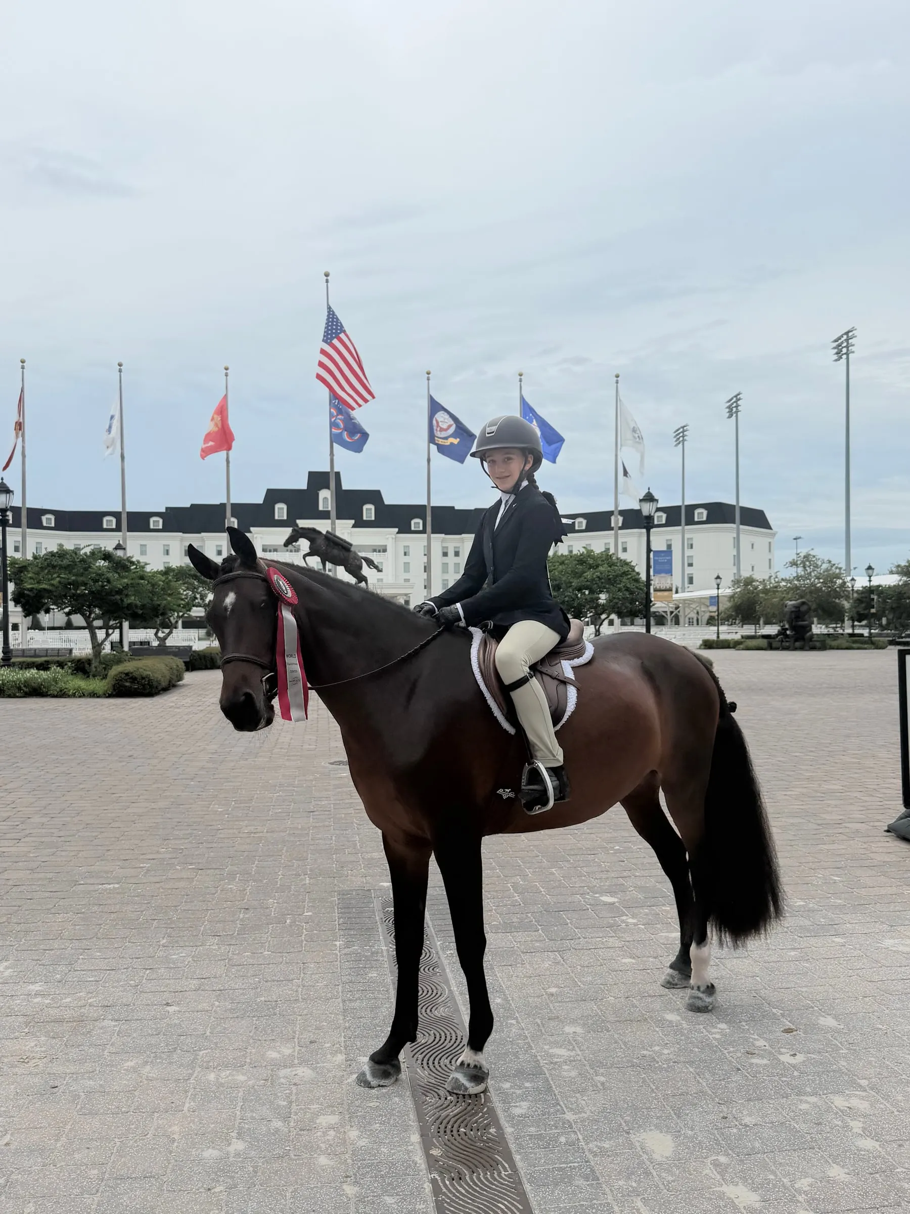 A rider on a black pony at World Equestrian Center under the flags